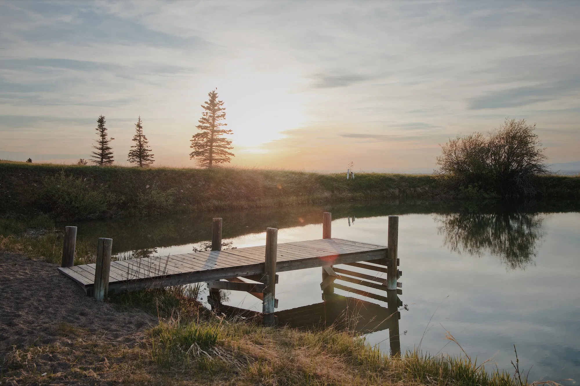 The dock on a still pond at golden hour